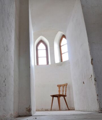 Weißer Kirchengang mit leerem Stuhl. Bild: Christine Immer, pfarrbriefservice.de